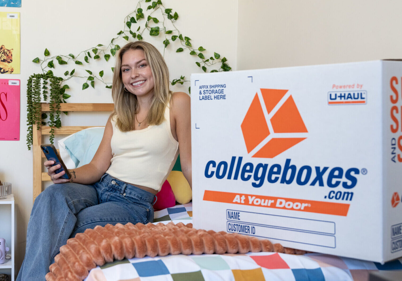Photo of a student in their dorm room with Collegeboxes branded boxes around the room.