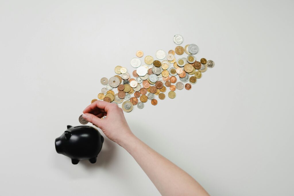 a hand putting coin into a piggy bank