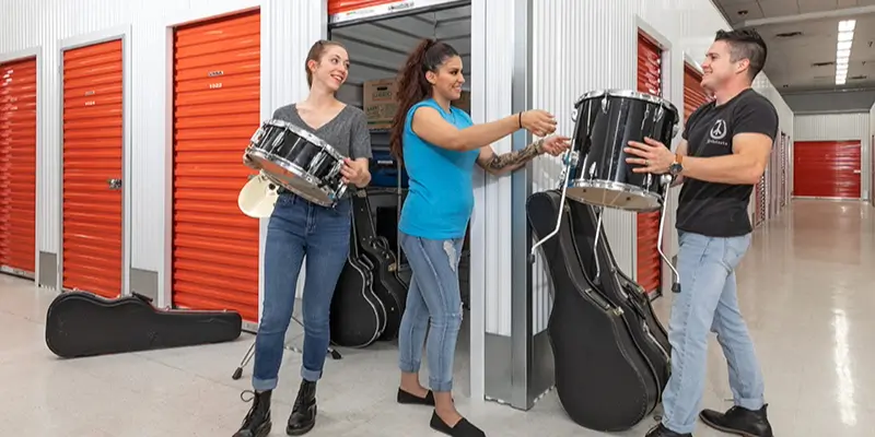 A group of students organizing their musical instruments in storage.